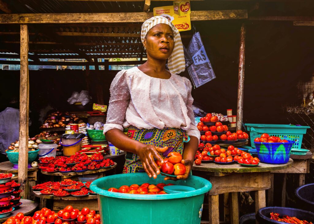 pexels photo 3213283 3213283 Woman selling fresh tomatoes at an outdoor market stall, showcasing vibrant produce.