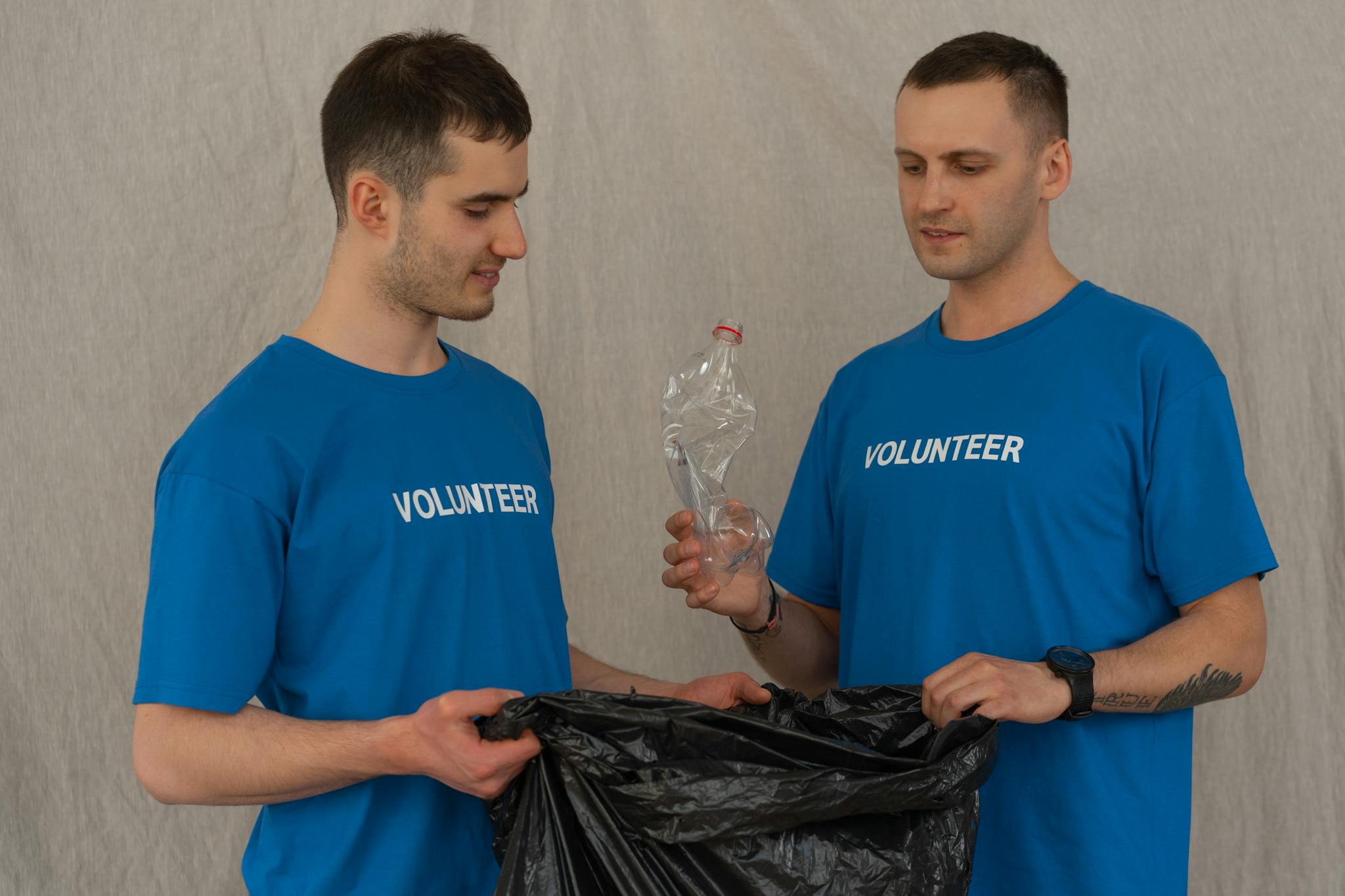 Two Male Volunteers In Blue Shirts Collecting