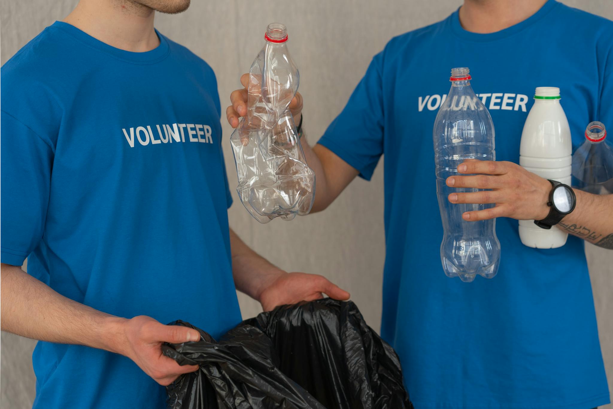 Two Volunteers In Blue Shirts Collect Plastic
