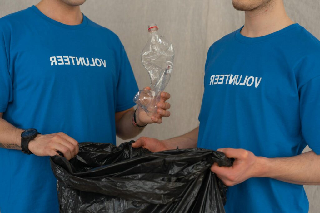 Two young volunteers collecting plastic for recycling, promoting environmental conservation.